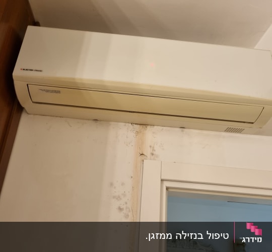 מזגן מותקן על קיר עם סימני רטיבות